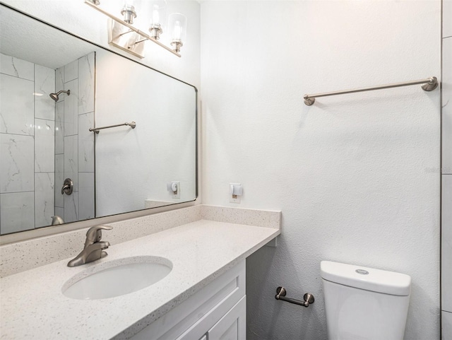 bathroom featuring a shower, toilet, and vanity