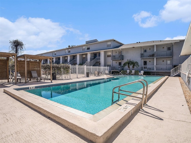 community pool with a patio and fence