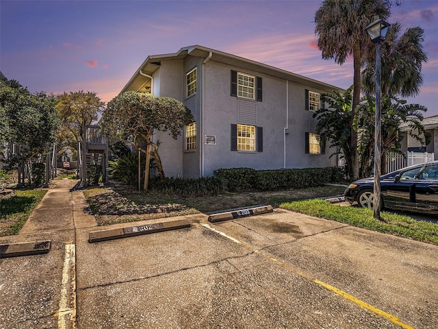 property exterior at dusk featuring stucco siding and uncovered parking