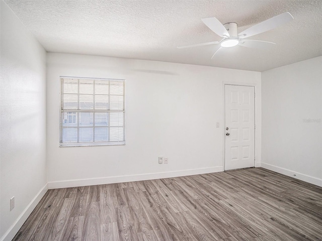 spare room featuring baseboards, a textured ceiling, ceiling fan, and wood finished floors