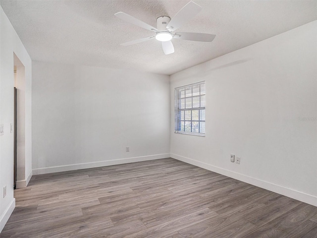 empty room featuring ceiling fan, baseboards, a textured ceiling, and wood finished floors