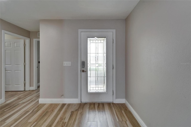 doorway with baseboards, light wood finished floors, and a healthy amount of sunlight