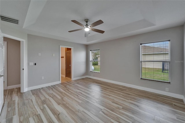 unfurnished bedroom featuring a tray ceiling, visible vents, and baseboards