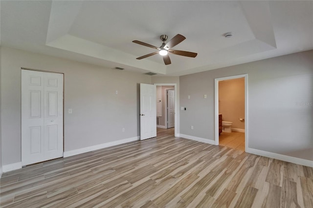 unfurnished bedroom with light wood finished floors, a raised ceiling, visible vents, and baseboards