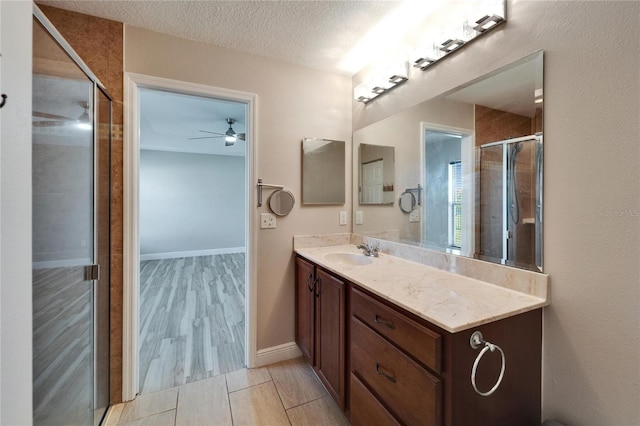 bathroom with a shower stall, ceiling fan, a textured ceiling, and vanity