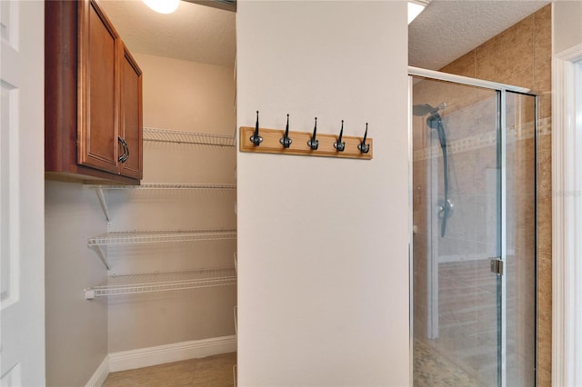 bathroom with a stall shower, a textured ceiling, and baseboards