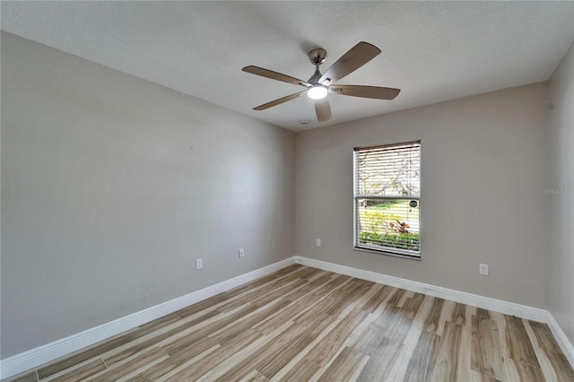 empty room featuring a textured ceiling, light wood-type flooring, a ceiling fan, and baseboards