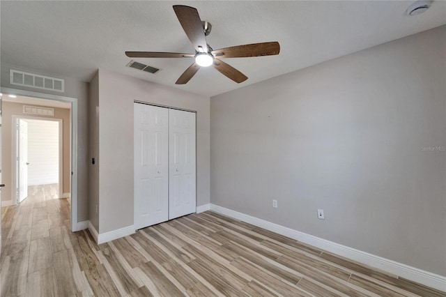 unfurnished bedroom with a closet, visible vents, light wood-style flooring, and baseboards