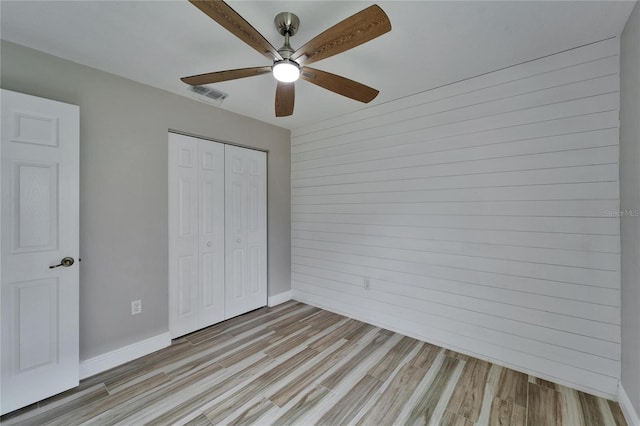 unfurnished bedroom with ceiling fan, light wood-style flooring, visible vents, baseboards, and a closet