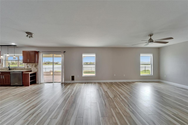 unfurnished living room featuring visible vents, ceiling fan, light wood-style flooring, and baseboards