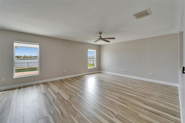 unfurnished room featuring visible vents, baseboards, light wood-style flooring, ceiling fan, and a textured ceiling