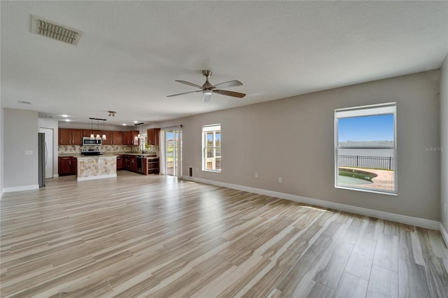 unfurnished living room with light wood-style floors, baseboards, and visible vents