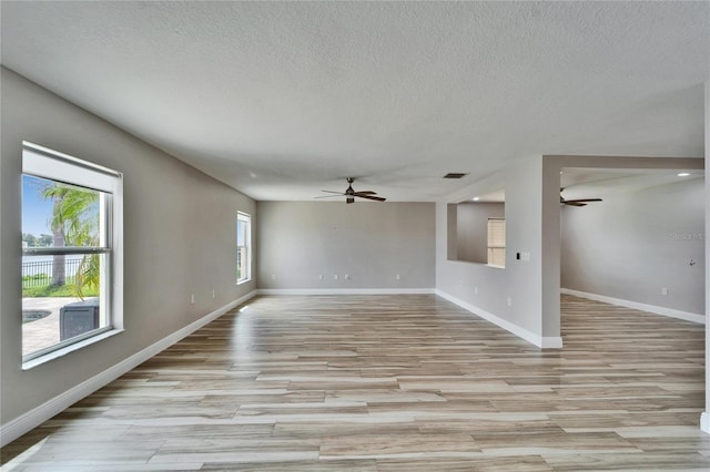 spare room featuring ceiling fan, a textured ceiling, baseboards, and light wood-style floors