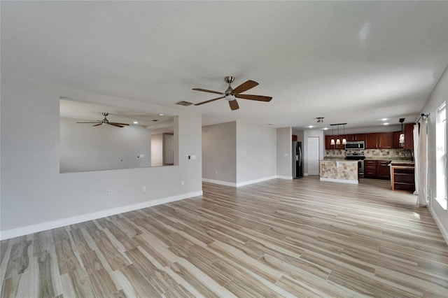 unfurnished living room featuring visible vents, ceiling fan, light wood-style flooring, and baseboards