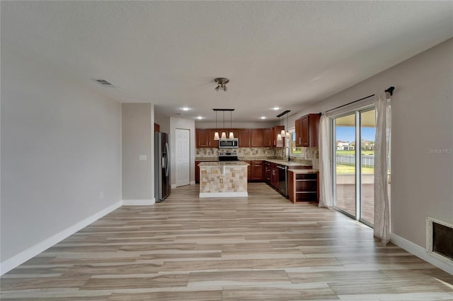 kitchen featuring visible vents, light countertops, appliances with stainless steel finishes, hanging light fixtures, and a center island