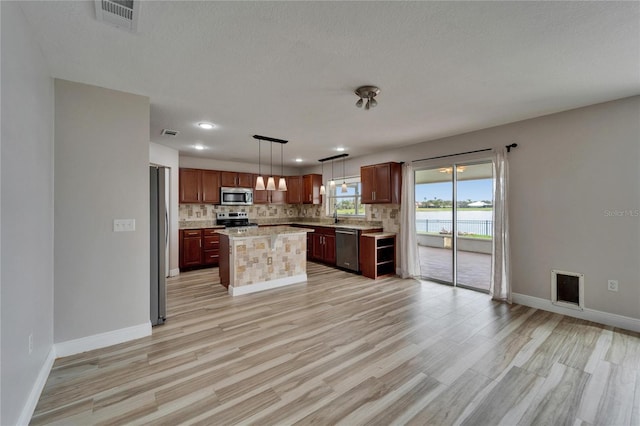 kitchen featuring tasteful backsplash, appliances with stainless steel finishes, a kitchen island, and pendant lighting