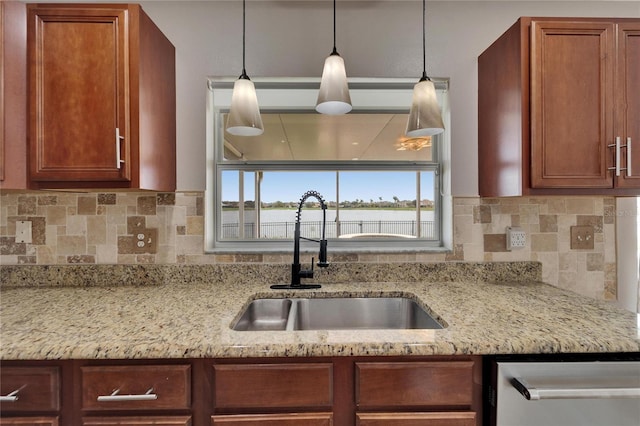 kitchen with decorative light fixtures, decorative backsplash, a sink, light stone countertops, and dishwasher