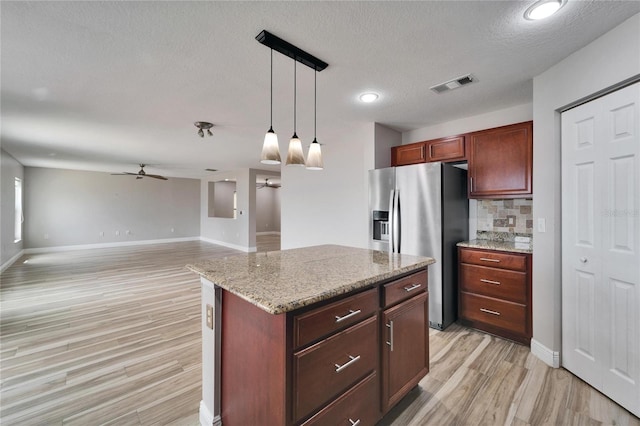 kitchen with a center island, pendant lighting, open floor plan, ceiling fan, and stainless steel fridge with ice dispenser