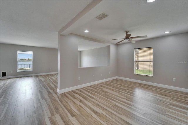 spare room featuring light wood-type flooring, visible vents, and baseboards