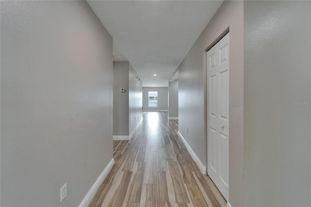 hallway featuring baseboards and light wood finished floors