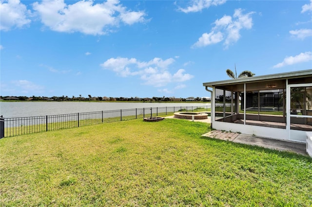 view of yard with a sunroom, a water view, fence, and a fire pit