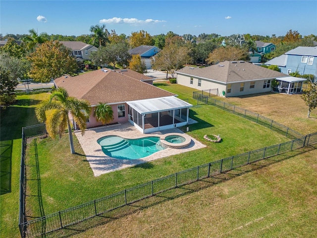 view of pool featuring a pool with connected hot tub, an outdoor fire pit, a sunroom, a residential view, and a fenced backyard