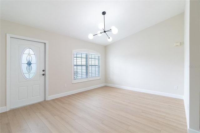 entryway featuring vaulted ceiling, an inviting chandelier, and light hardwood / wood-style flooring