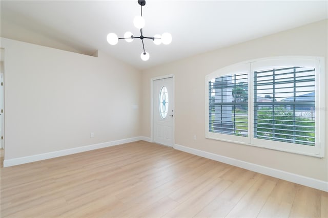 foyer featuring light hardwood / wood-style floors, vaulted ceiling, and a notable chandelier