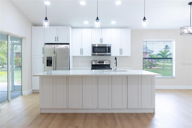 kitchen with a center island with sink, stainless steel appliances, and white cabinetry