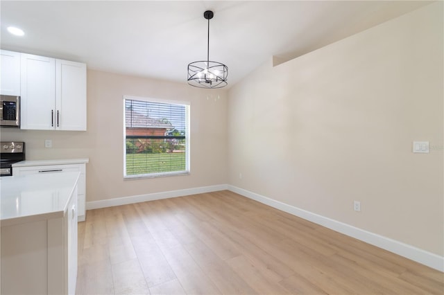 unfurnished dining area with a chandelier and light hardwood / wood-style flooring