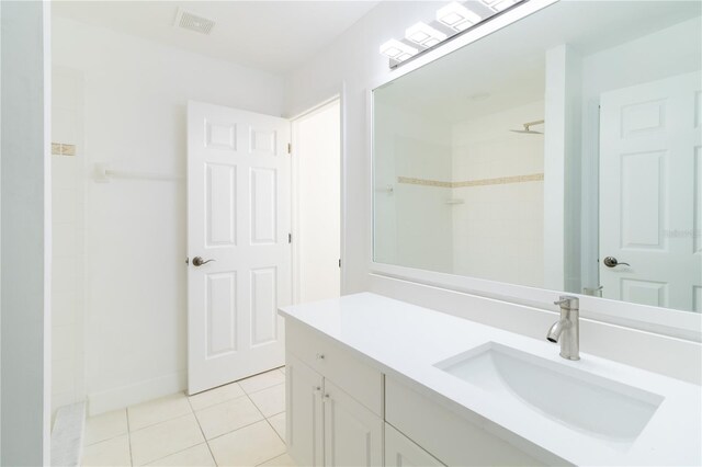 bathroom with tile patterned flooring, vanity, and walk in shower