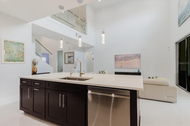 kitchen with sink, a towering ceiling, decorative light fixtures, stainless steel dishwasher, and dark brown cabinetry