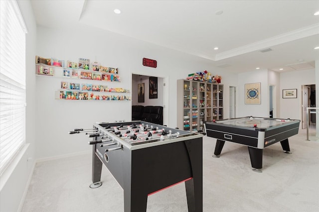 recreation room featuring a tray ceiling, crown molding, light colored carpet, and a healthy amount of sunlight