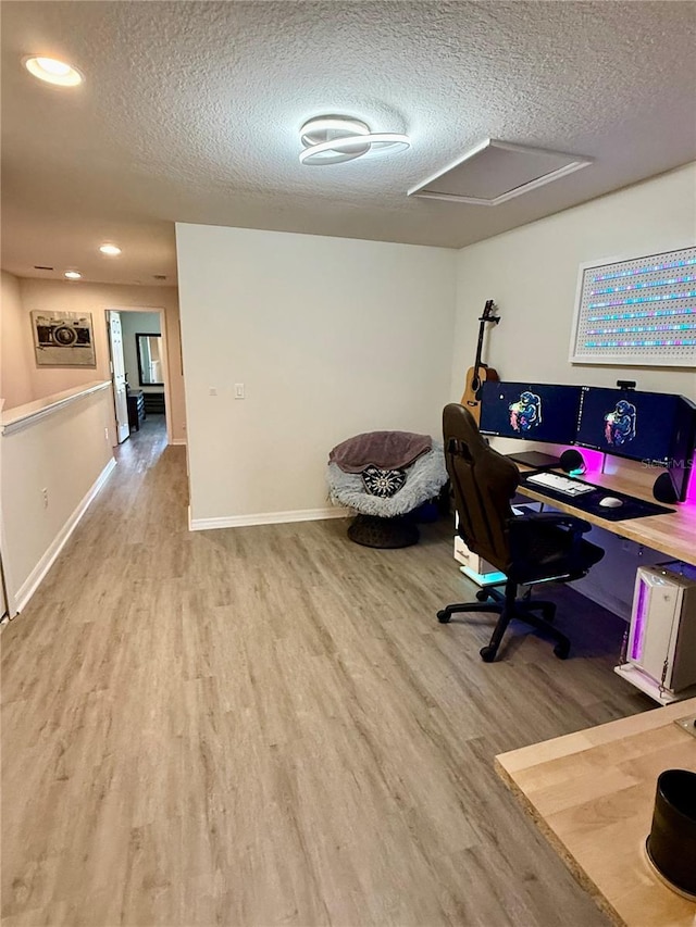 office with a textured ceiling, wood finished floors, attic access, and baseboards