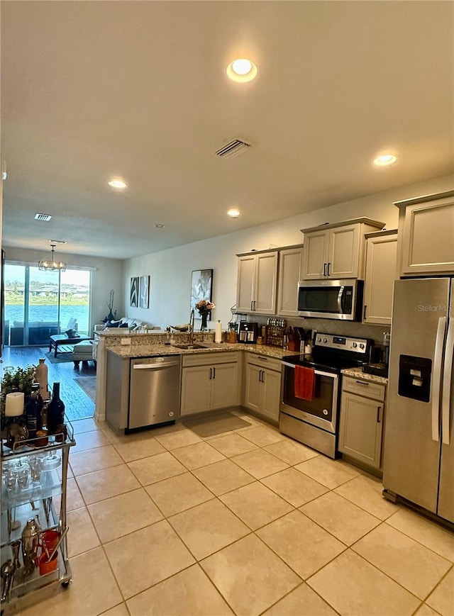 kitchen featuring gray cabinetry, a peninsula, a sink, visible vents, and appliances with stainless steel finishes