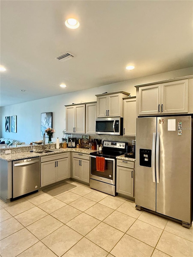 kitchen with appliances with stainless steel finishes, a sink, visible vents, and gray cabinetry