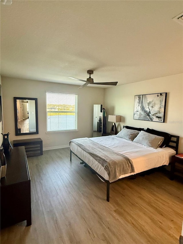 bedroom featuring light wood-style floors, visible vents, ceiling fan, and baseboards