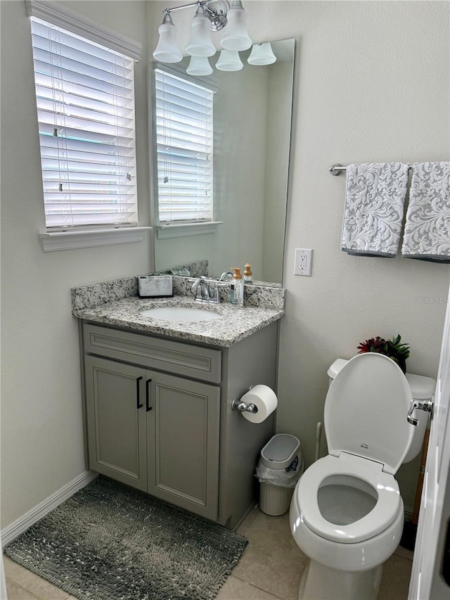 bathroom with baseboards, toilet, tile patterned floors, an inviting chandelier, and vanity