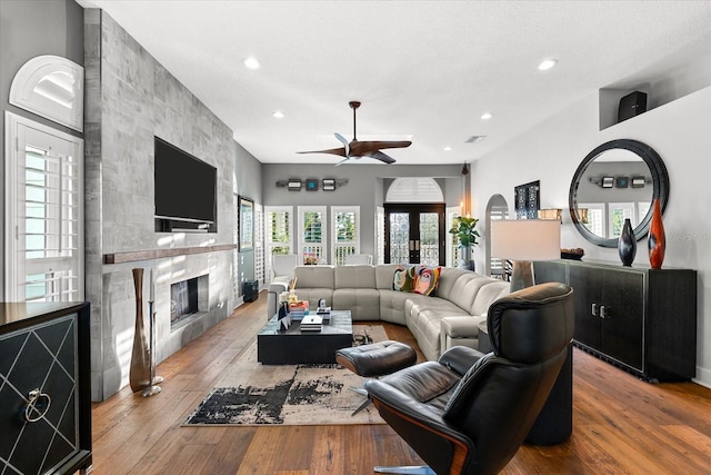 living room with visible vents, recessed lighting, a tile fireplace, a ceiling fan, and wood-type flooring