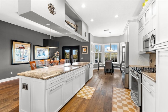 kitchen featuring appliances with stainless steel finishes, white cabinetry, light wood-type flooring, and a sink