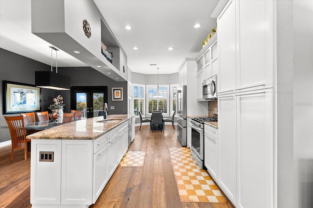 kitchen featuring a sink, a spacious island, appliances with stainless steel finishes, and white cabinetry