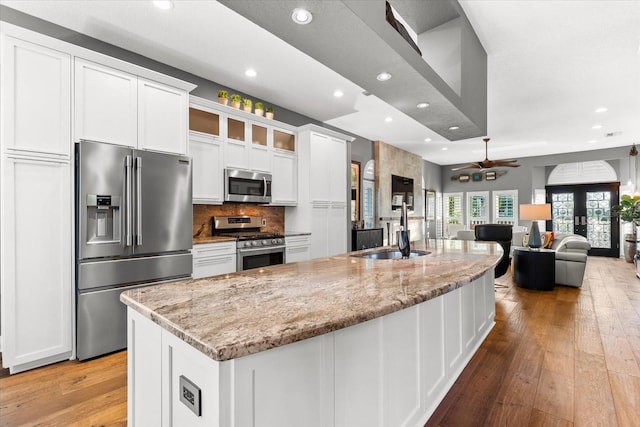 kitchen with a sink, stainless steel appliances, light wood-style flooring, and white cabinetry