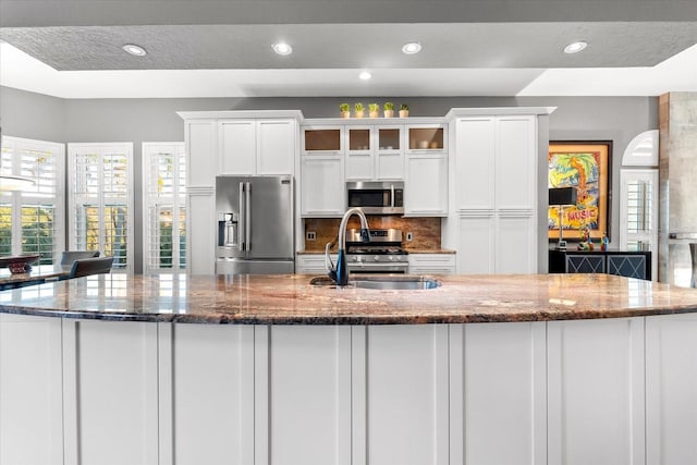 kitchen featuring a sink, backsplash, appliances with stainless steel finishes, and white cabinetry