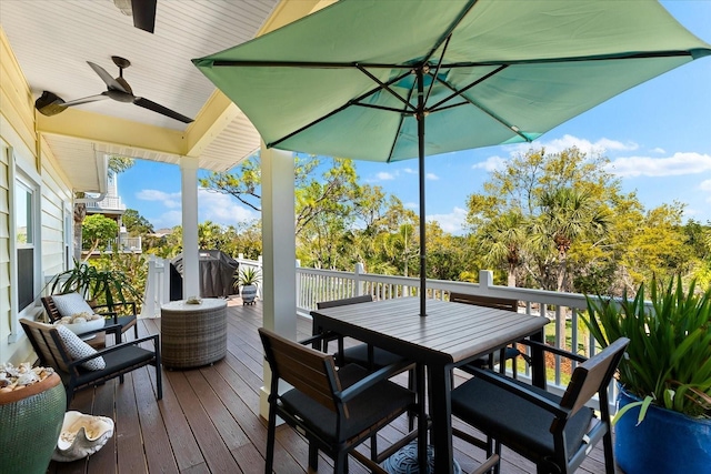 wooden terrace with outdoor dining area and a ceiling fan