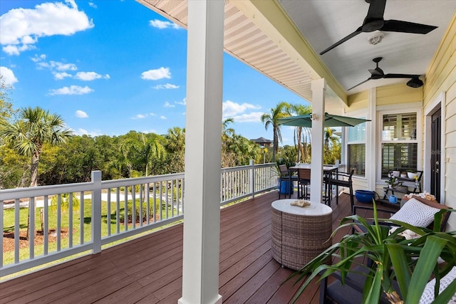 wooden deck with outdoor dining area and a ceiling fan