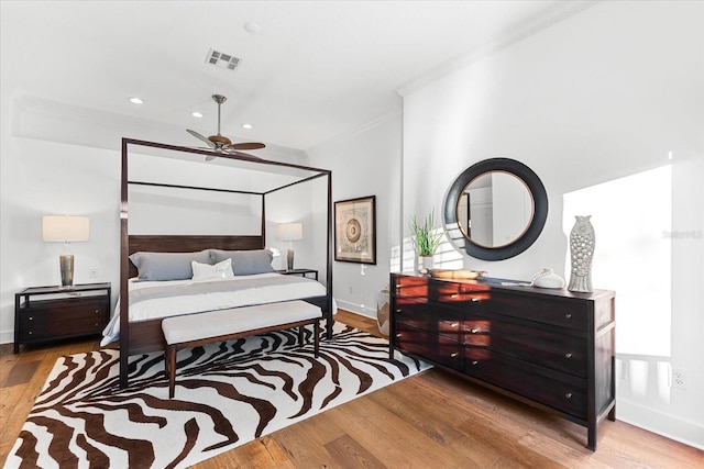 bedroom featuring wood finished floors, visible vents, baseboards, recessed lighting, and crown molding