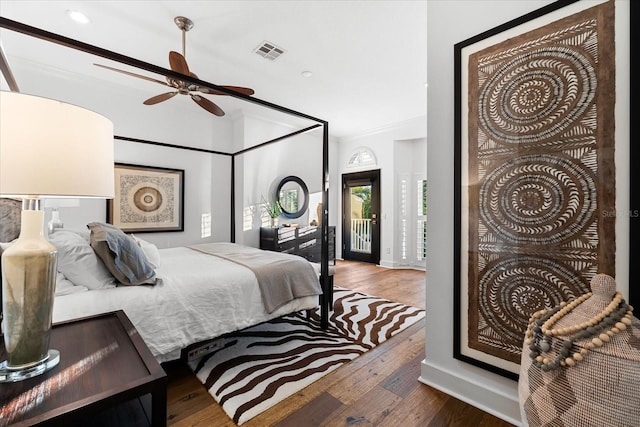 bedroom featuring a ceiling fan, wood finished floors, visible vents, ornamental molding, and access to exterior