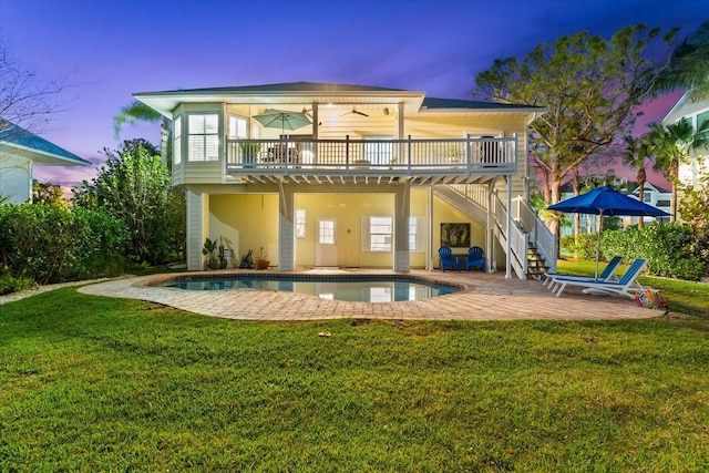 rear view of property with stairs, a lawn, a deck, an outdoor pool, and a patio