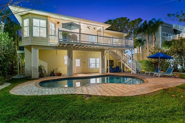 rear view of house featuring a lawn, a patio, stairway, an outdoor pool, and a wooden deck