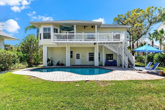 rear view of house featuring a lawn, a deck, an outdoor pool, stairs, and a patio area